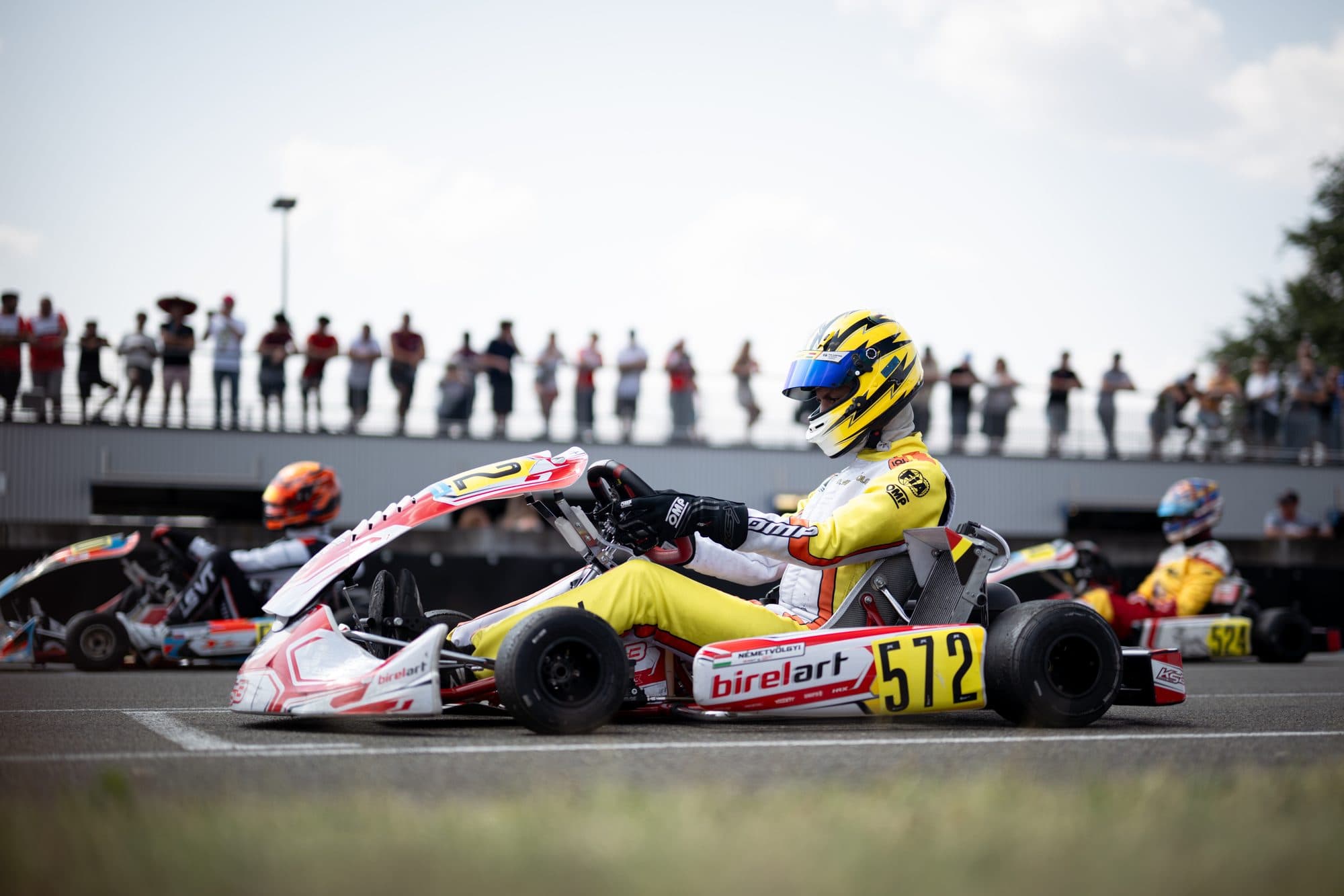 Kart #572 on track with spectators in the background, Le Mans